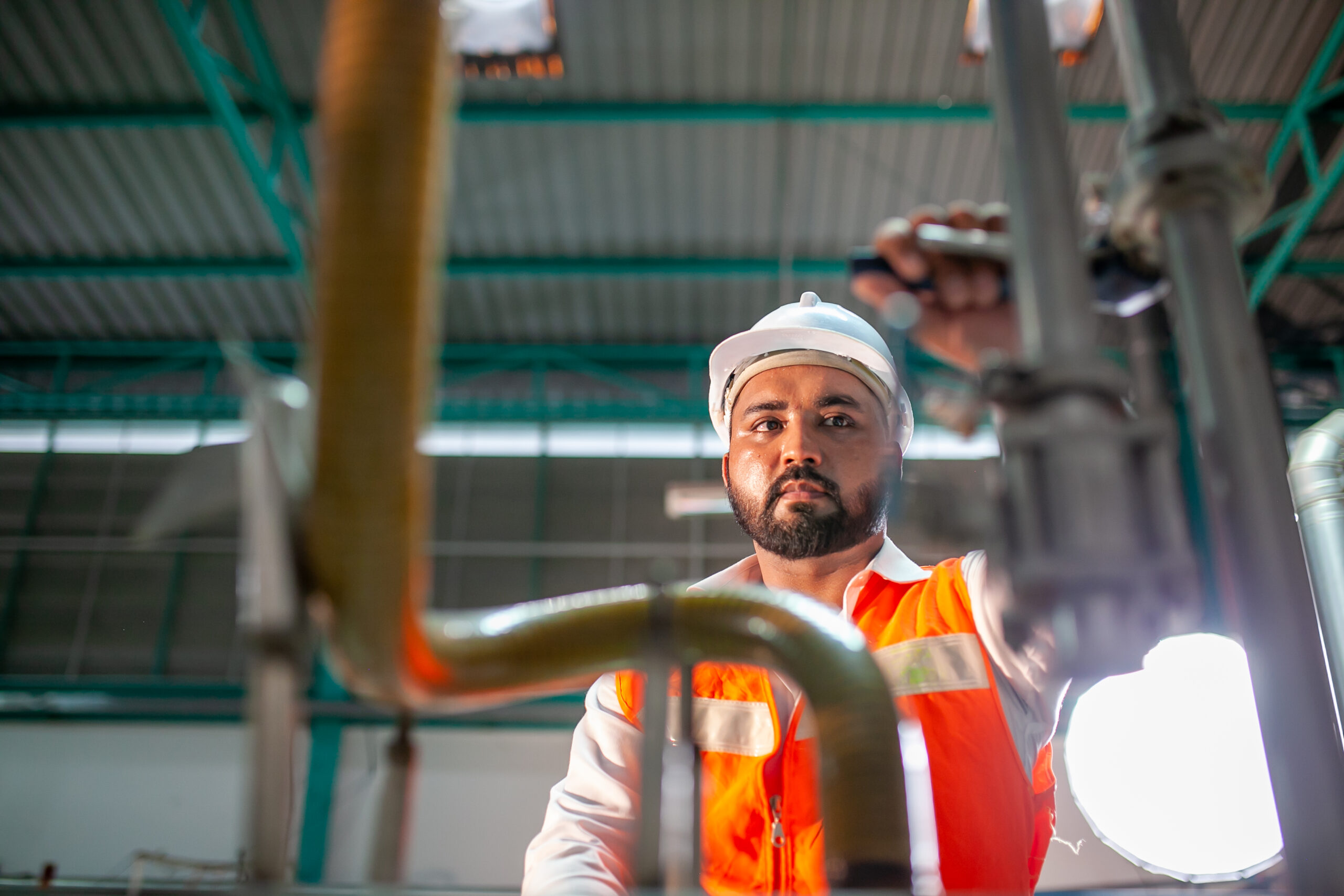 professional technician engineer with safety hard hat working to maintenance construction equipment in industrial factory, worker is checking or repair the machine.